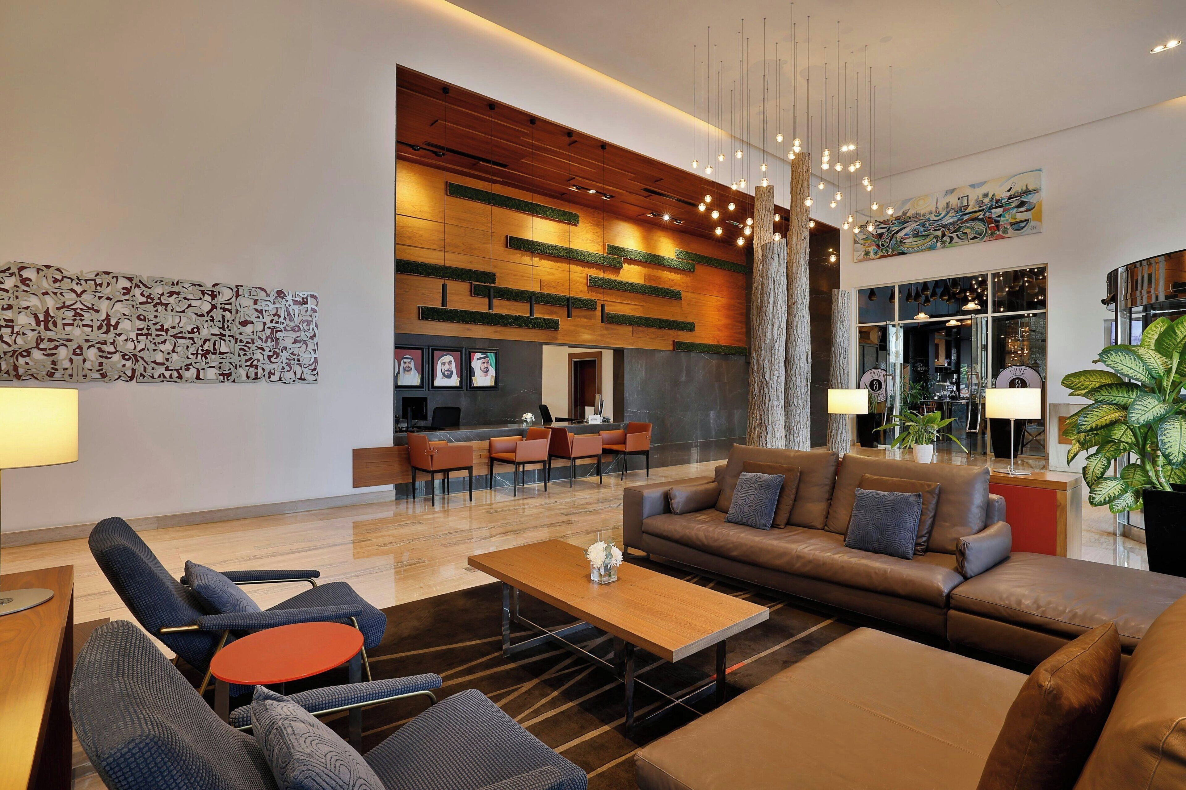 A modern lobby with a reception desk, seating area, and a large plant.