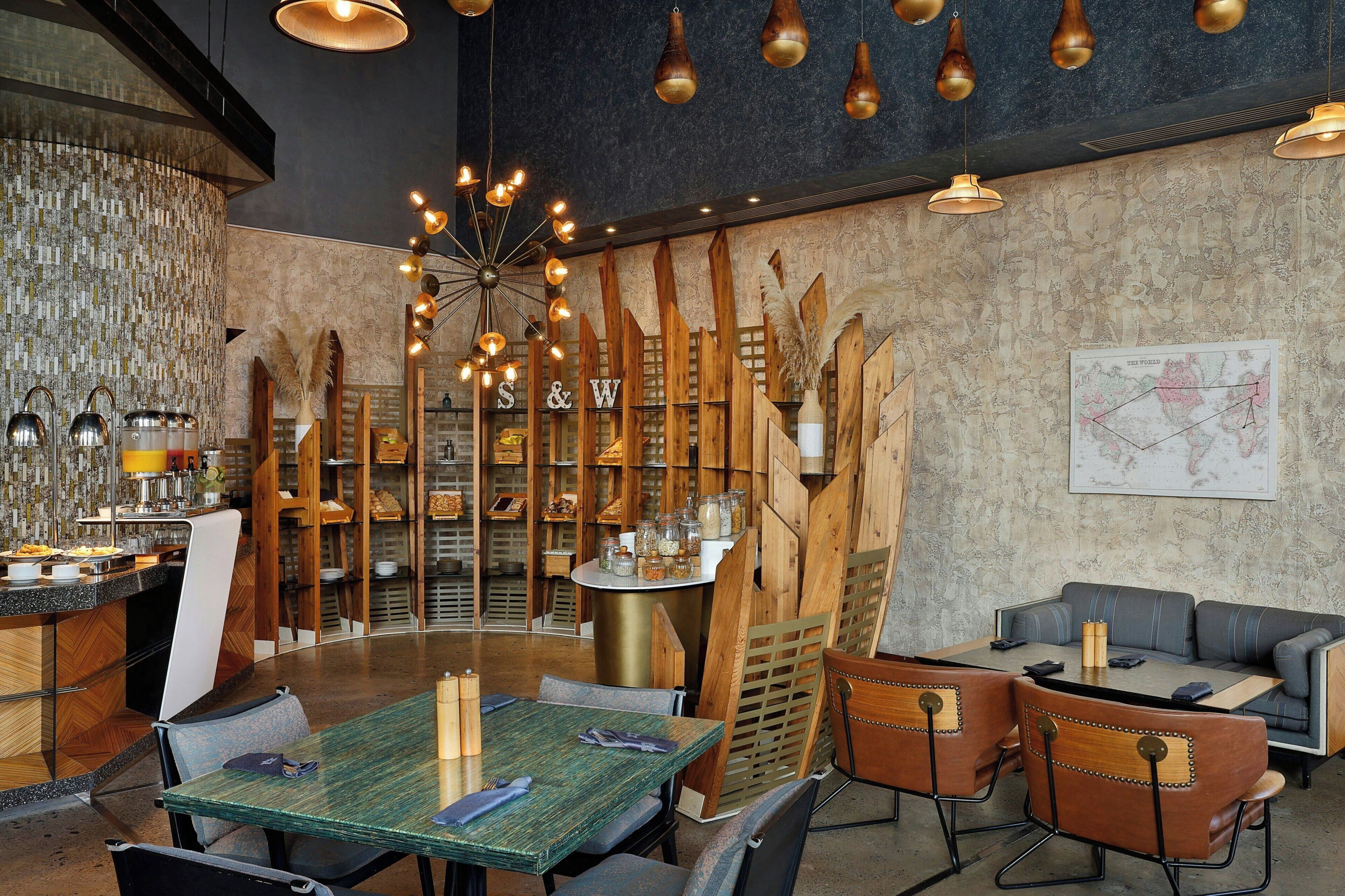 A restaurant with a round table, wooden chairs, and a bar area with stools.