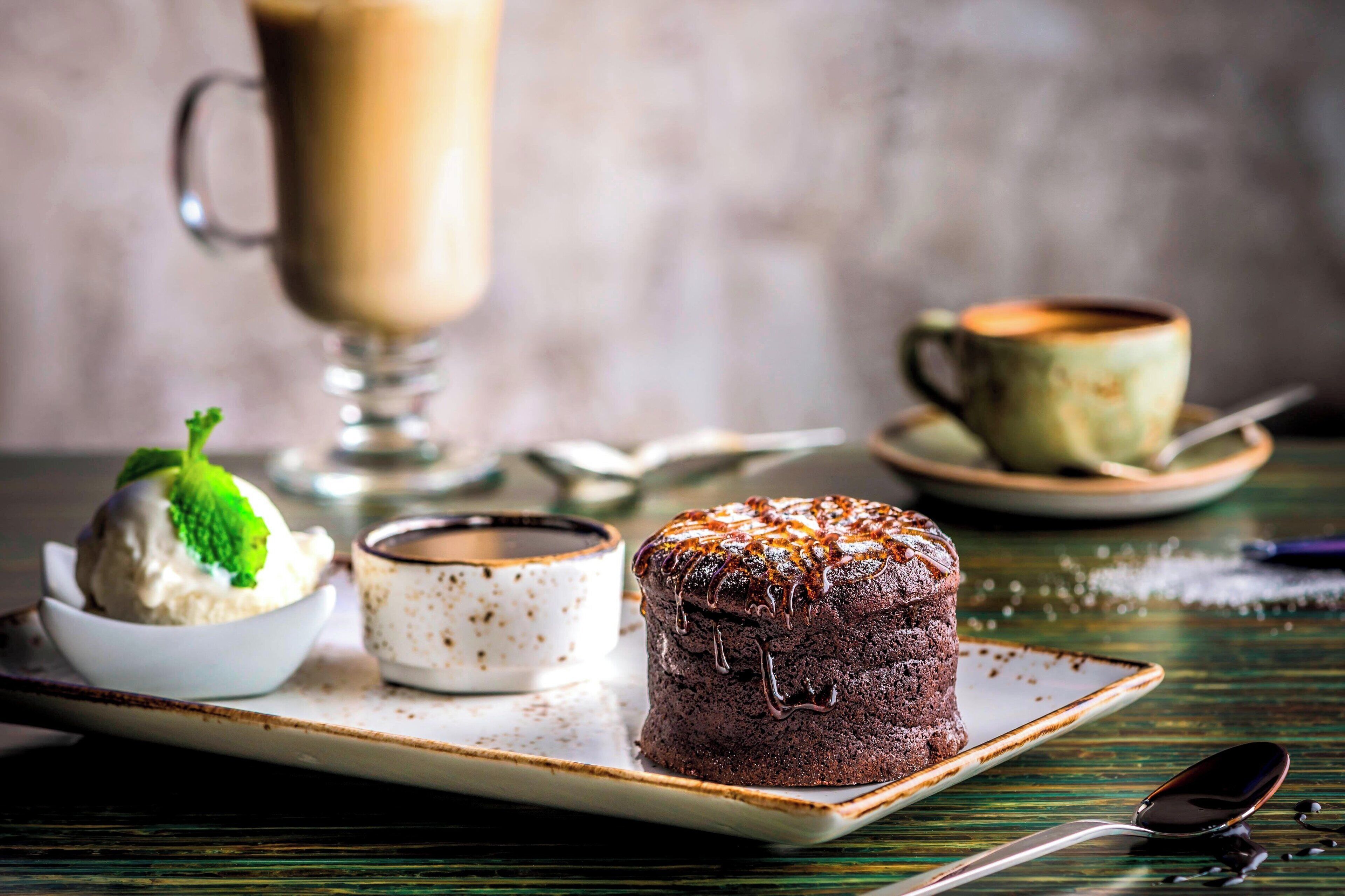 Um prato de sobremesa com bolo de chocolate, uma taça de sorvete e uma xícara de café.