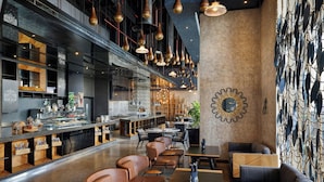 Een modern restaurant met een lange toonbank, lederen zitplaatsen en hanglampen.