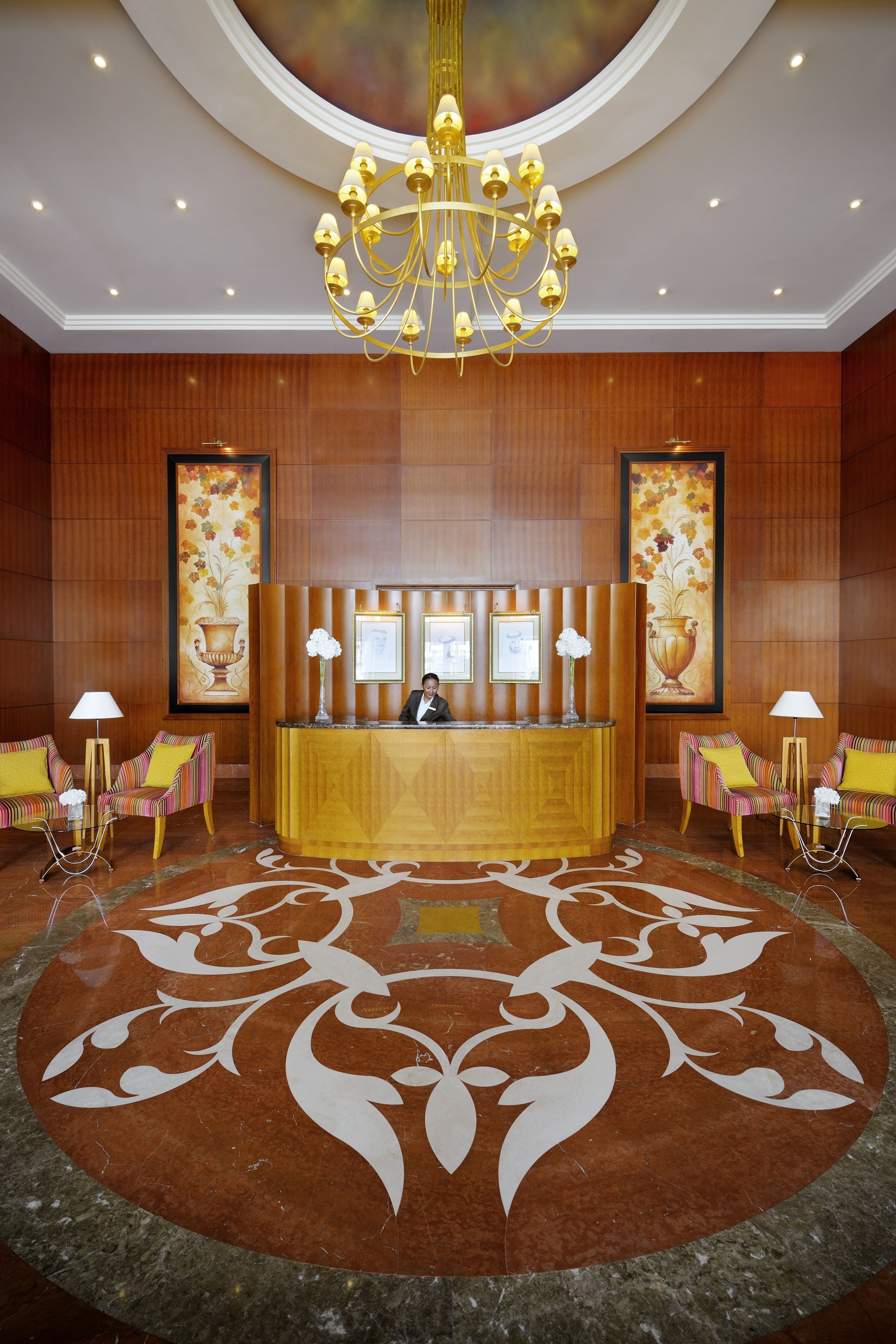 A lobby with a reception desk, two sofas, a chandelier, and framed artwork on the walls.