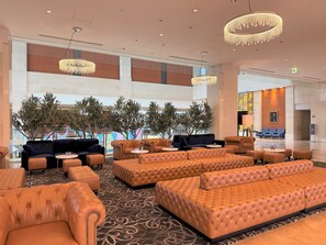 A spacious lobby with leather sofas, a patterned carpet, and a chandelier. - Hotel Keihan Universal Tower (Osaka)