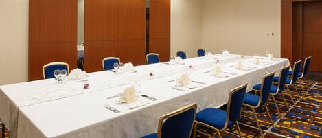 Un salón de conferencias con una larga mesa, sillas azules y una alfombra estampada.