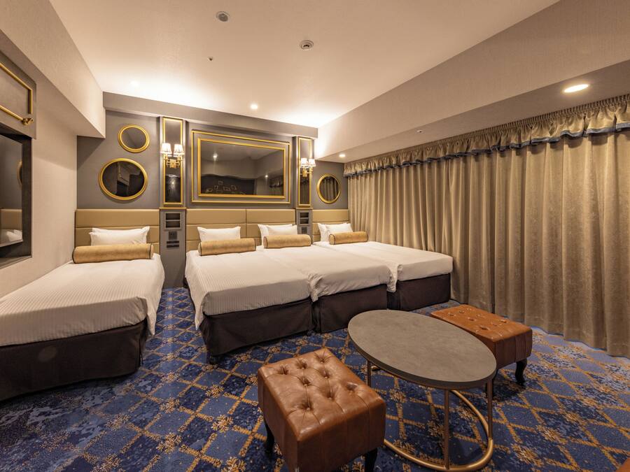 A hotel room with two beds, a round table, a small ottoman, and a large mirror.