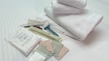 Un juego de artículos de aseo de cama ordenado, que incluye gel de ducha, toalla, cepillo para el cabello, cepillo de dientes y varios productos de cuidado personal.