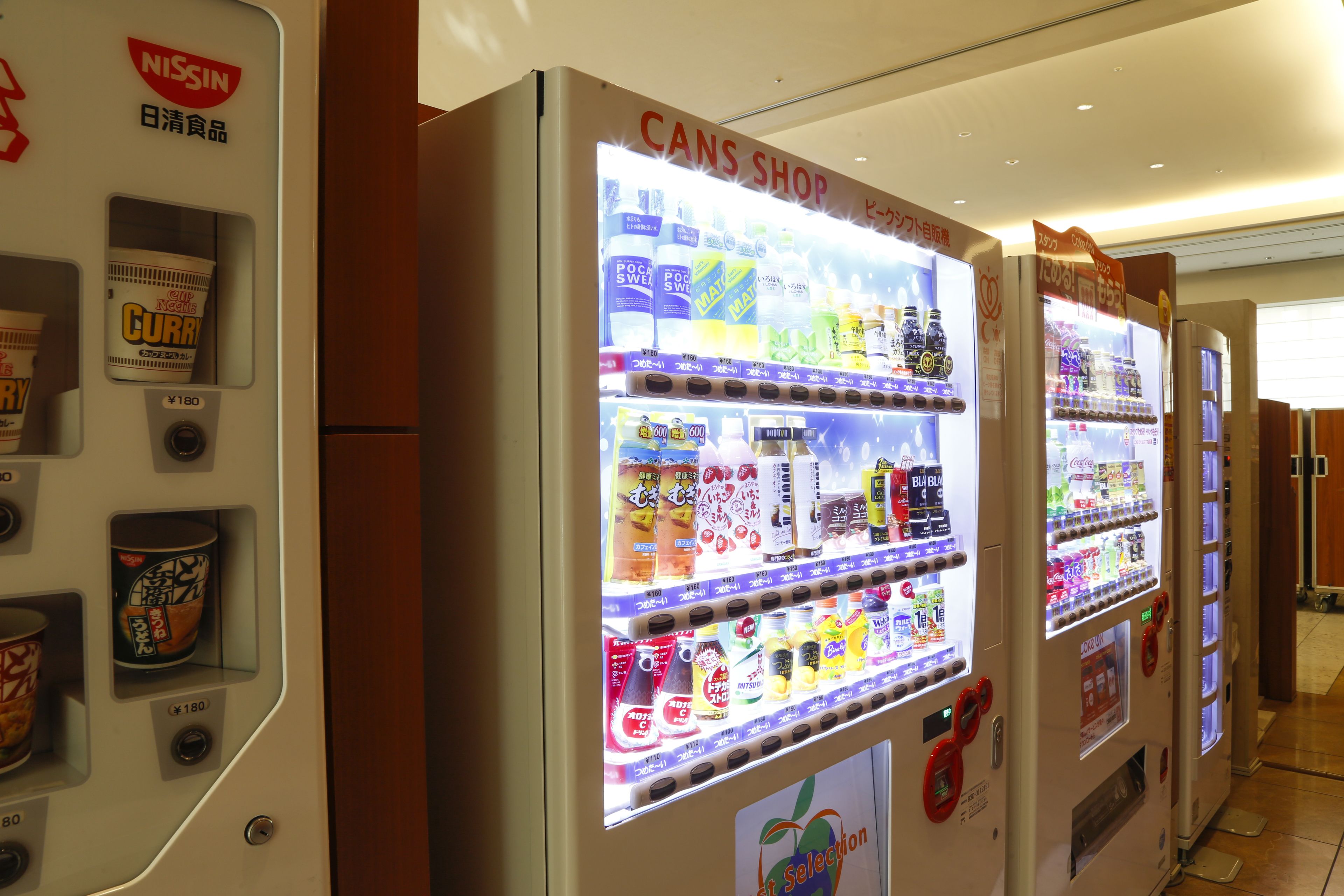 Vending machines with a variety of beverages and snacks, including a selection of cans and bottles.