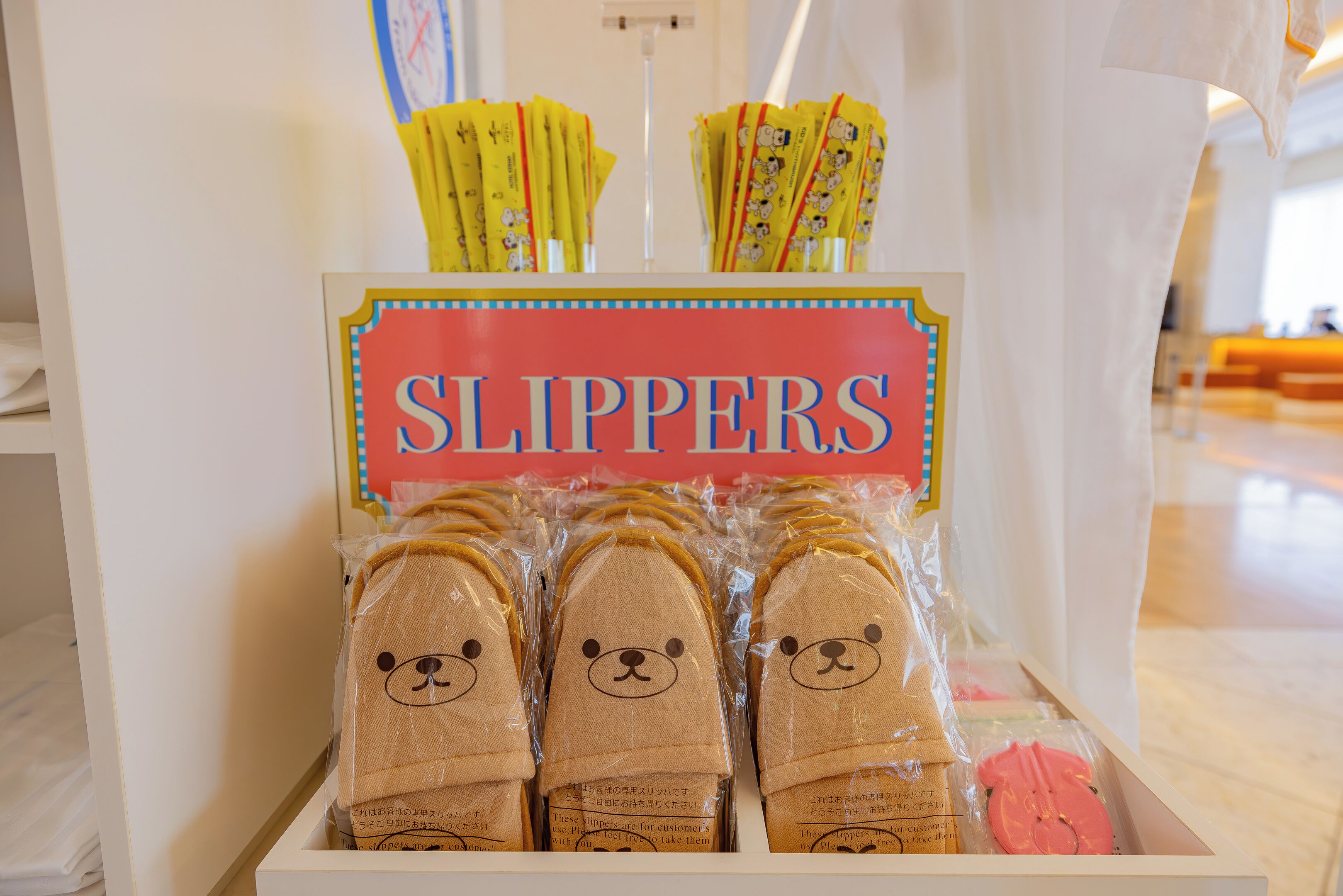 A display of slippers with a sign reading "SLIPPERS" in a store.