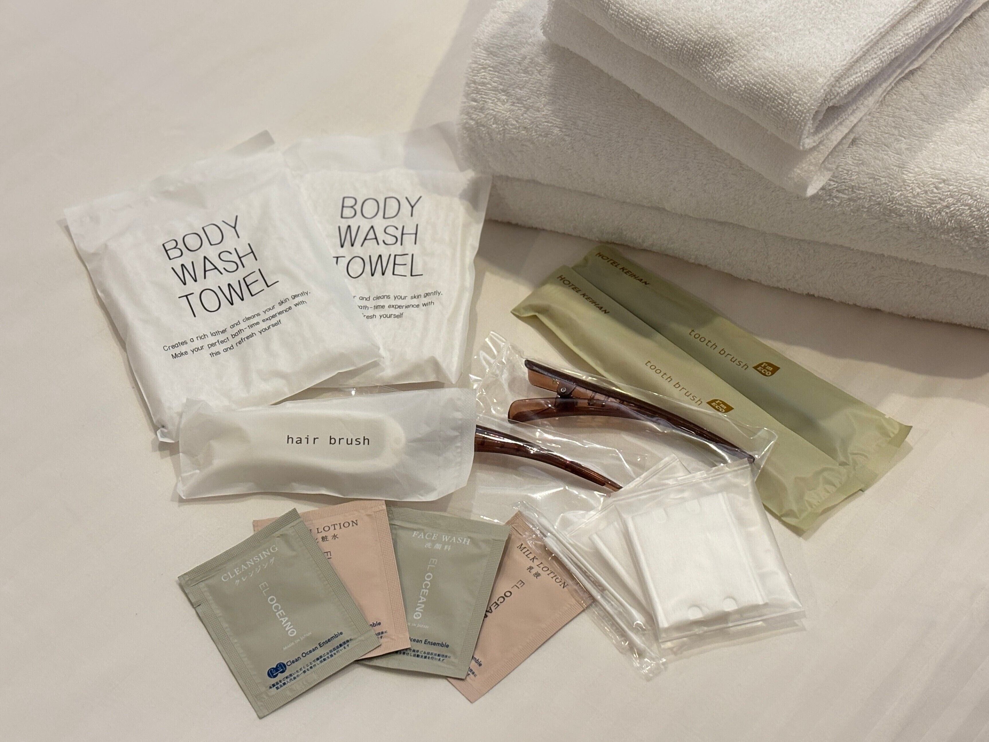 A neatly arranged set of toiletries including body wash towels, hair brush, and various personal care items on a clean surface.
