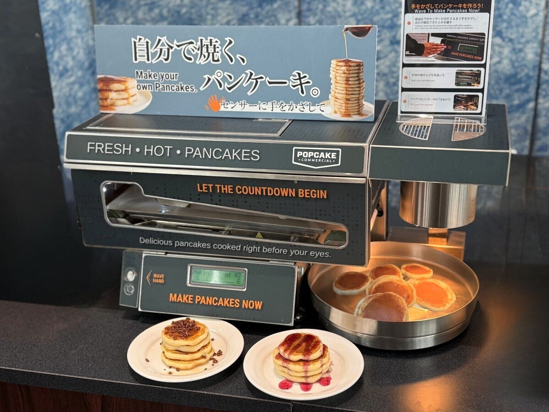 A commercial kitchen with a sign that reads 'FRESH • HOT • PANCAKES' and a digital display indicating 'Making Pancakes Now.'