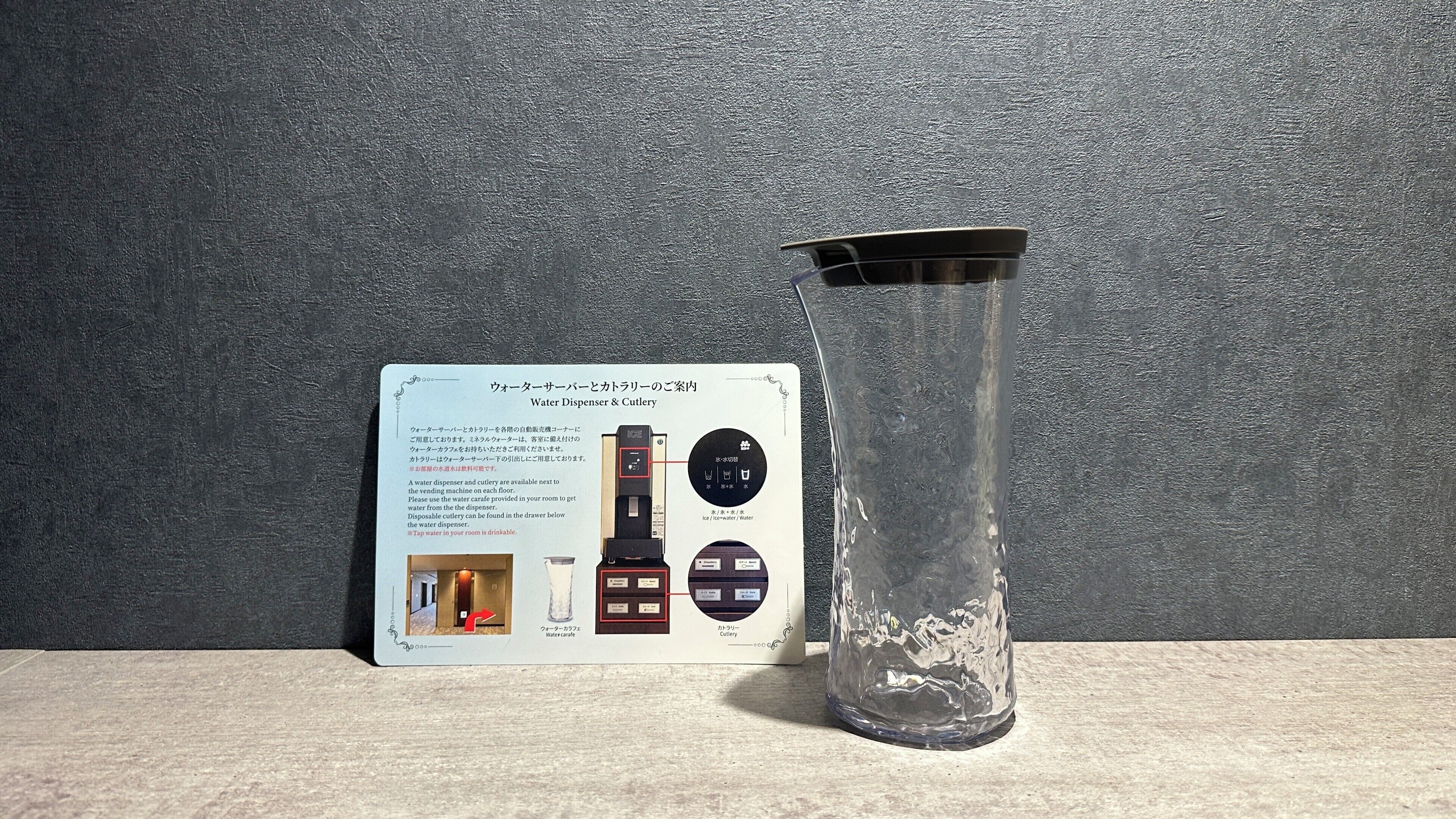 A water dispenser and cutlery set with a glass container beside it.