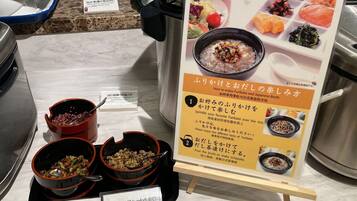 Mostra de menjar amb bols de rice i verdures, un cartell amb text japonès i un taulell amb safata blava.