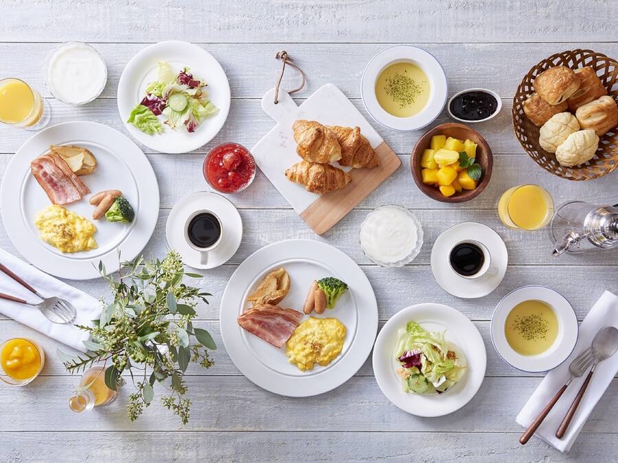 A breakfast buffet with various dishes including eggs, bacon, toast, and pastries.