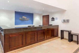 A reception desk with a blue sign reading "Baymont Inn & Suites."
