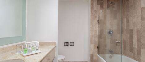 Un baño moderno con encimera de mármol, ducha con mampara de vidrio y un inodoro.