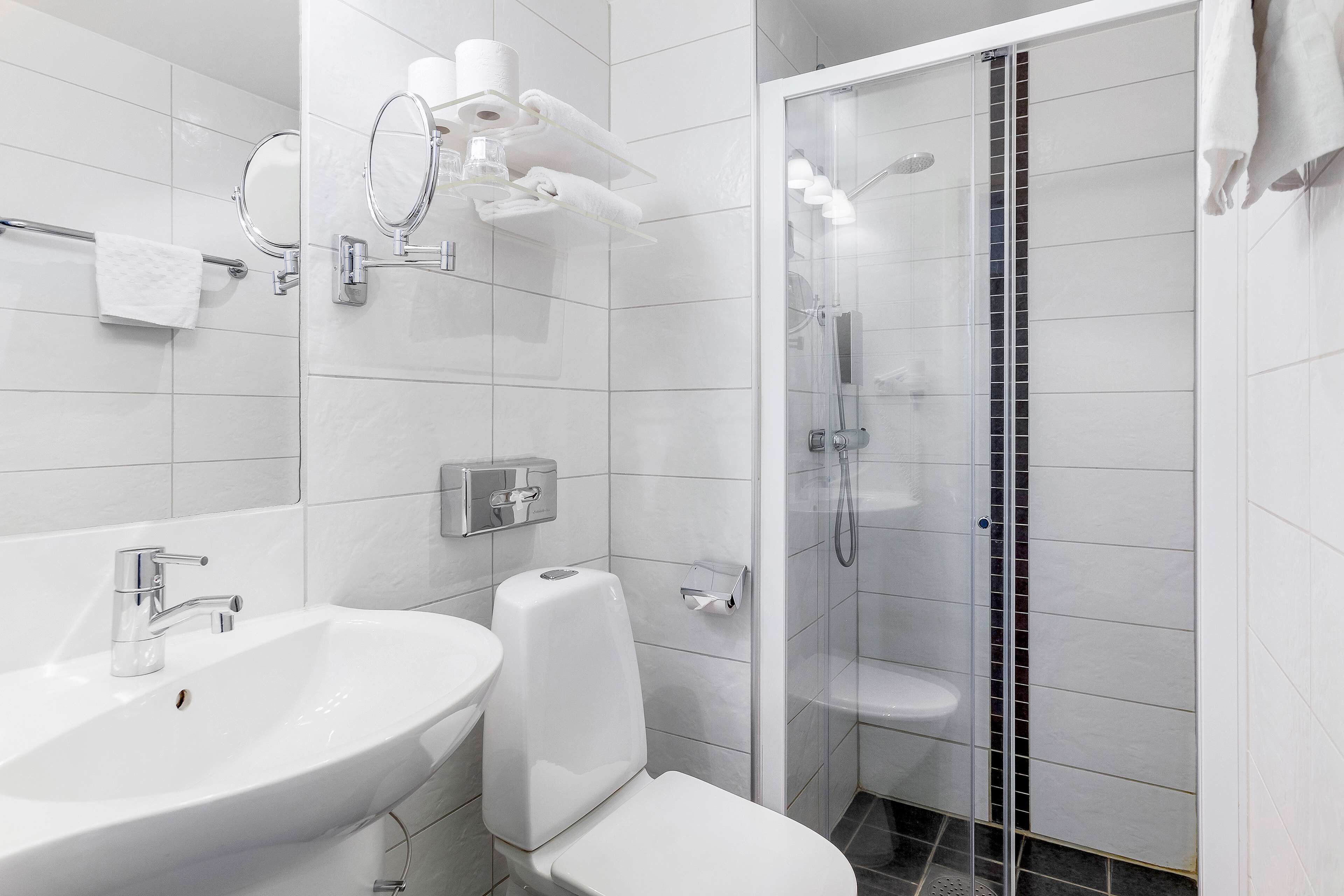 A modern bathroom with a white sink, toilet, and shower area.