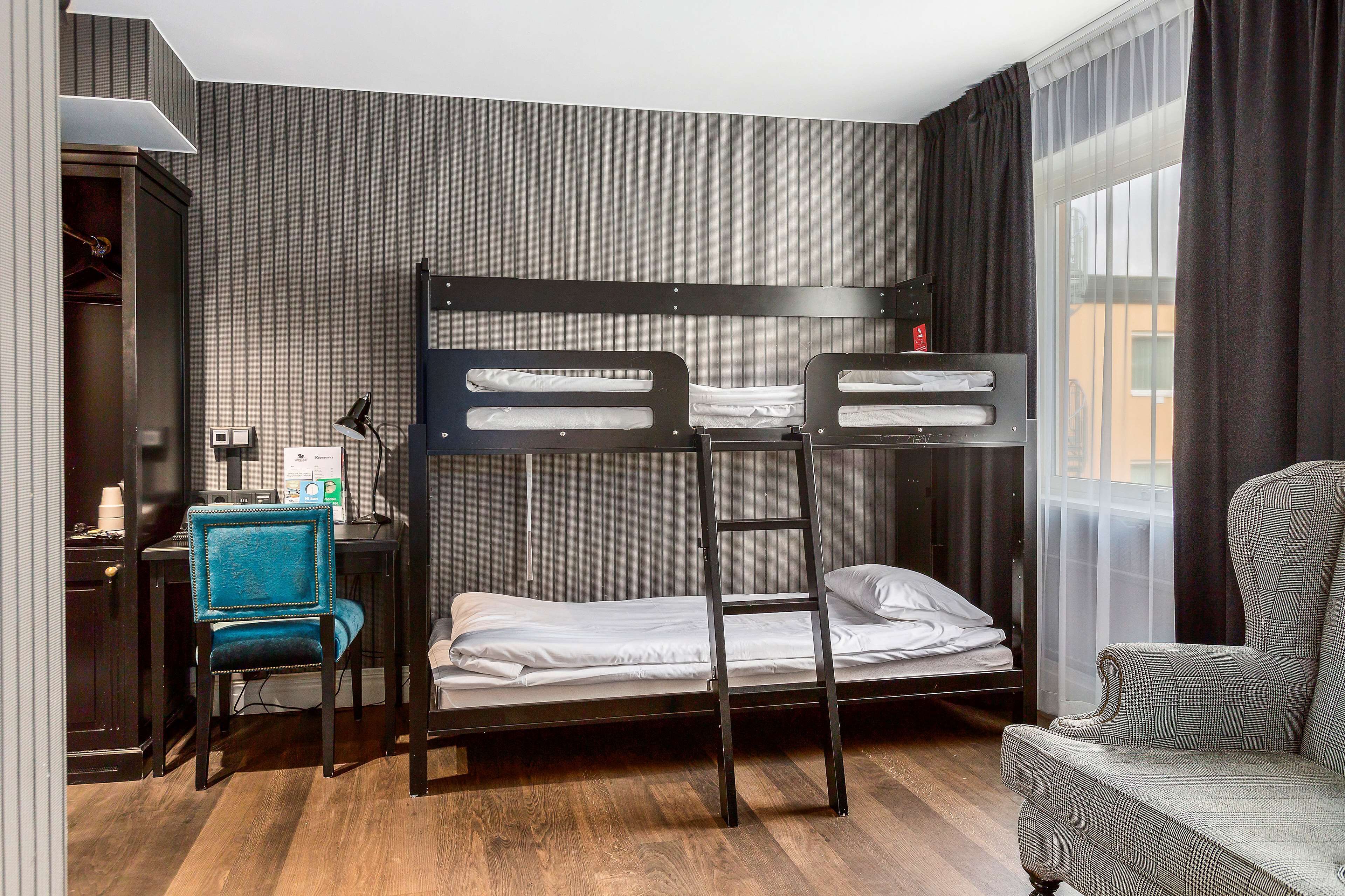 A bunk bed room with a desk, chair, and a view of the outside.