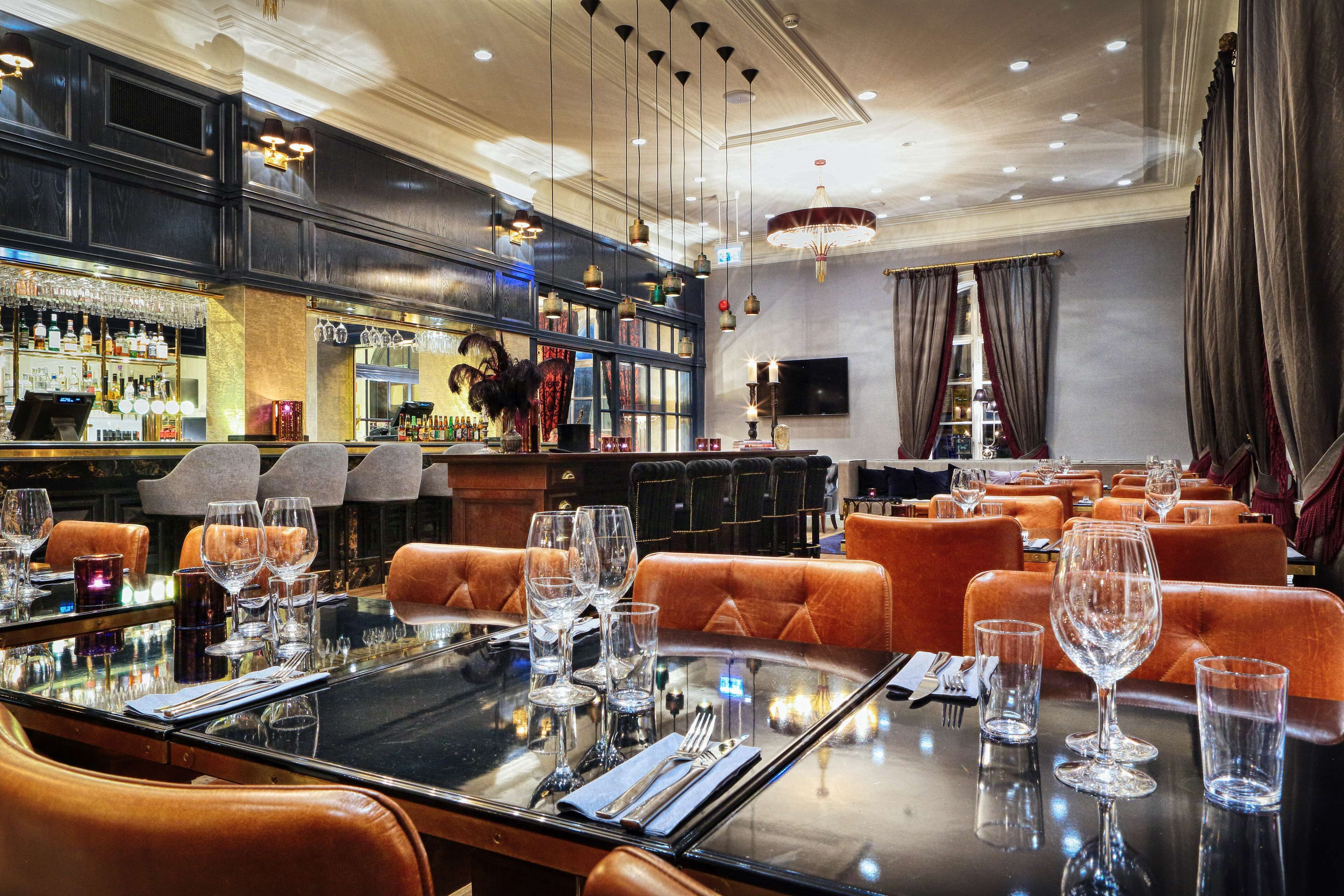 A bar area with a long counter, multiple seating options, and a television screen.