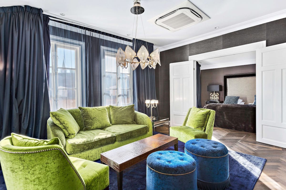 A modern living room with a green sofa, blue ottomans, and a wooden coffee table.