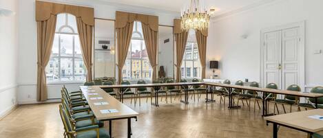 A conference room with a long table, chairs, and large windows with curtains.