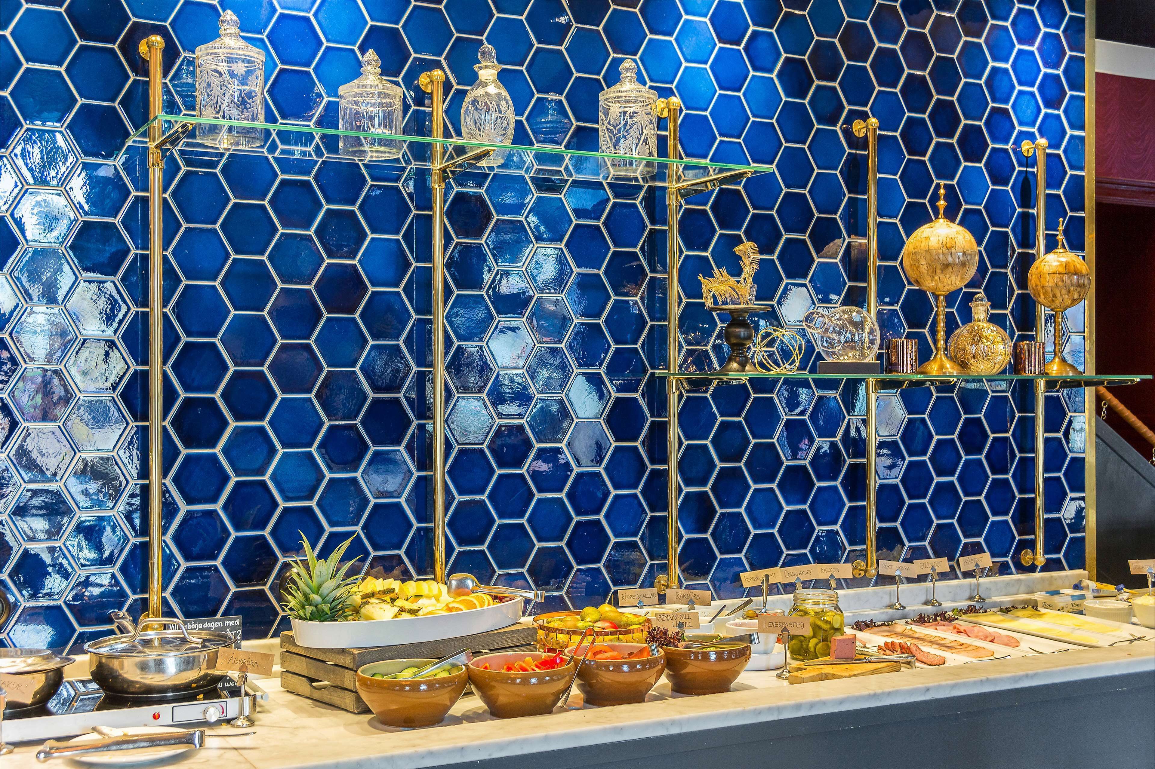 A buffet with various food items and decorative glassware against a blue hexagonal tile wall.