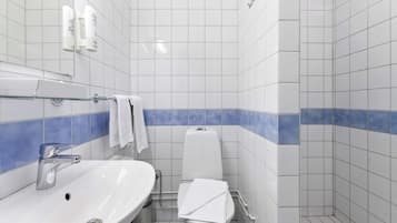 A bathroom with a white sink, a toilet, and a shower area.