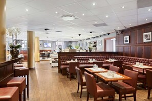 A restaurant with wooden flooring, leather booths, and tables with white placemats. - Best Western Vetlanda Stadshotell (Vetlanda)