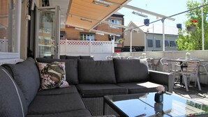 A covered outdoor seating area with a sofa, chairs, and a table.
