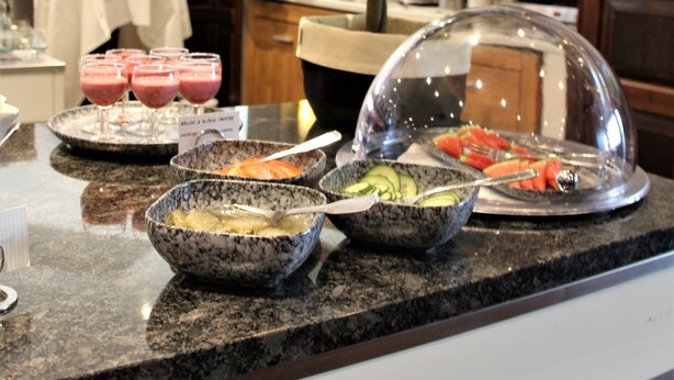 A buffet setup with various food items and beverages on a granite countertop.