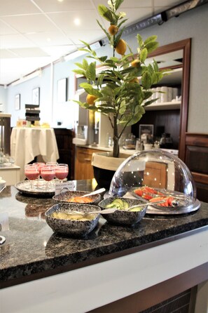 A buffet setup with various food items and beverages on a granite countertop.