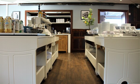 A kitchen area with white cabinetry, a coffee machine, and various food items on the counter.