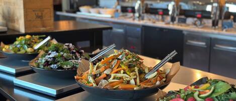 A buffet with various salads and dishes on trays.