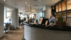 Zona de bar moderna con mostrador de recepción, teléfono y cartel de menú.
