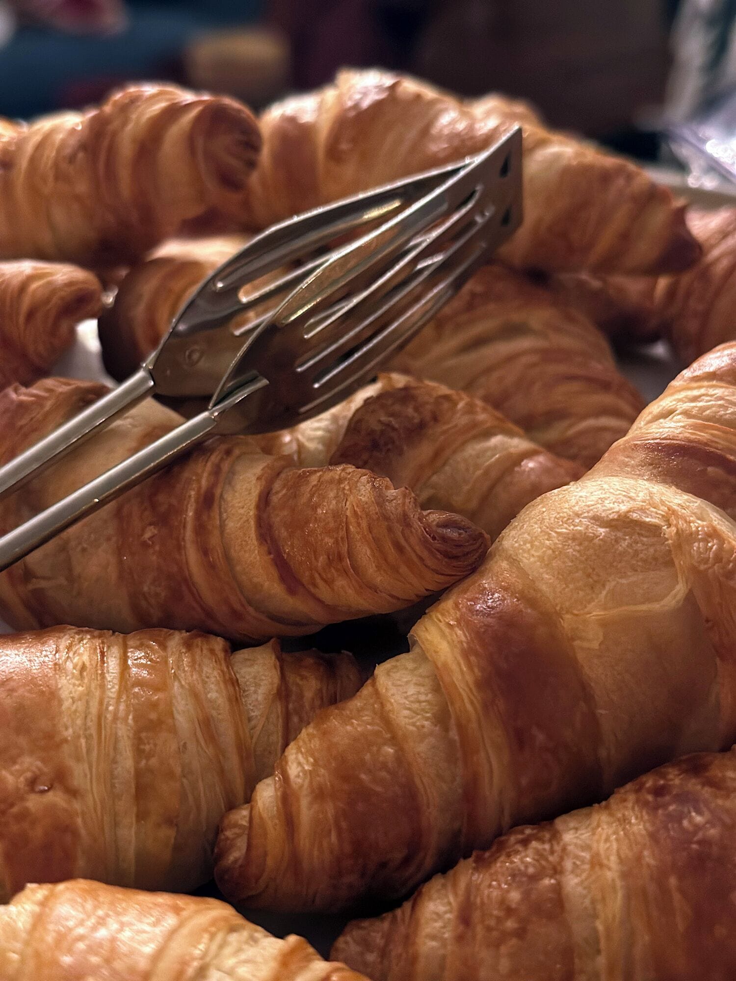 A close-up of golden-brown croissants with a fork resting on top.