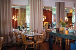 A restaurant with wooden chairs and tables, candles, and flowers on the tables. - Mjolby Stadshotell (Mjolby)
