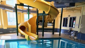 Una piscina interior con un tobogán amarillo y una superficie de agua azul cristalina.