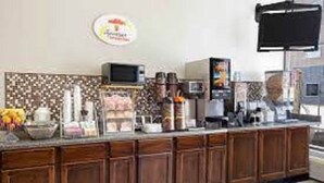 Una cocina con estación de café, microondas y refrigerador.