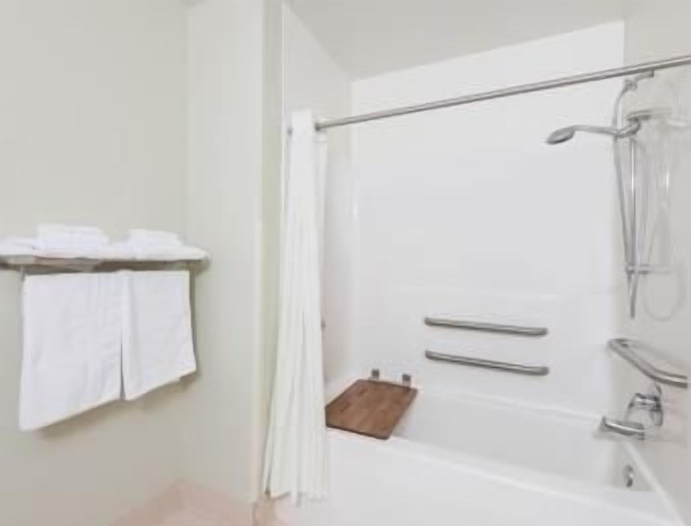 Une salle de bain moderne équipée d’une douche, d’un porte-serviettes et d’un petit tabouret en bois.