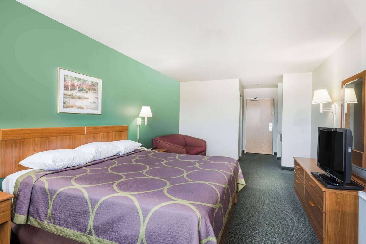 A hotel room with a bed, a television, a desk, and a chair.