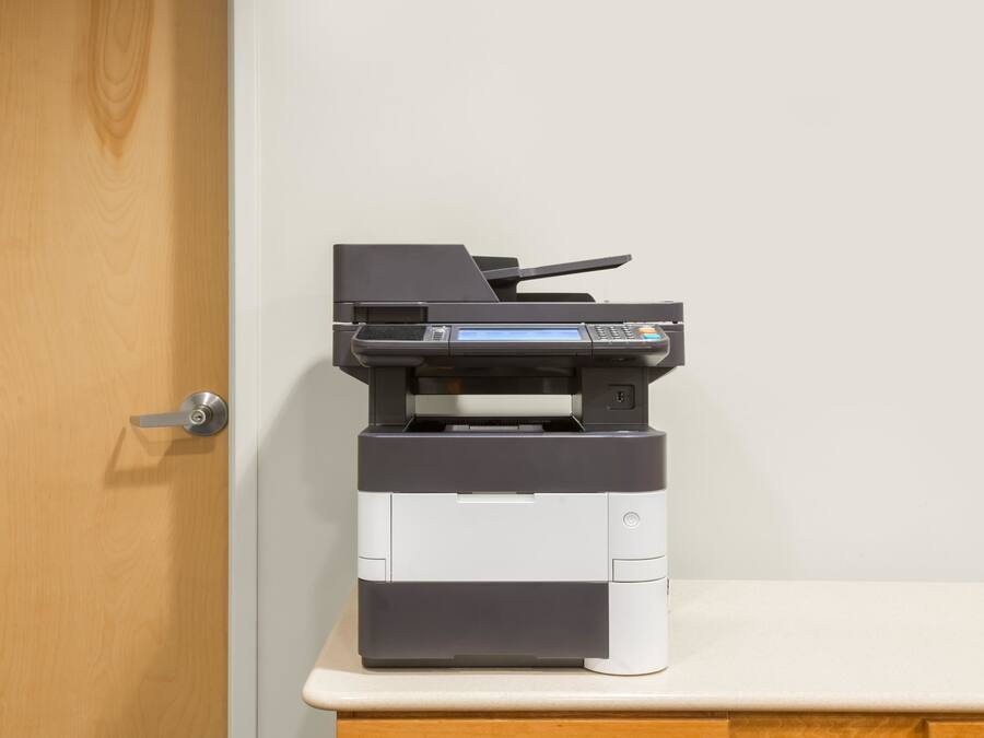 A printer on a desk next to a wooden door.