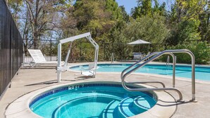 A swimming pool with a diving board, lounge chairs, and a fence. - Creekside Inn & Suites (Willits)