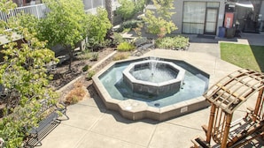 A courtyard with a hot tub, a wooden bench, and a Coca-Cola vending machine. - Creekside Inn & Suites (Willits)