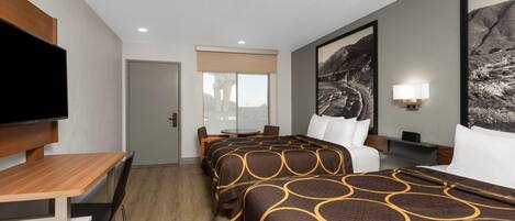A hotel room with a bed, a desk, a chair, a TV, and a window.