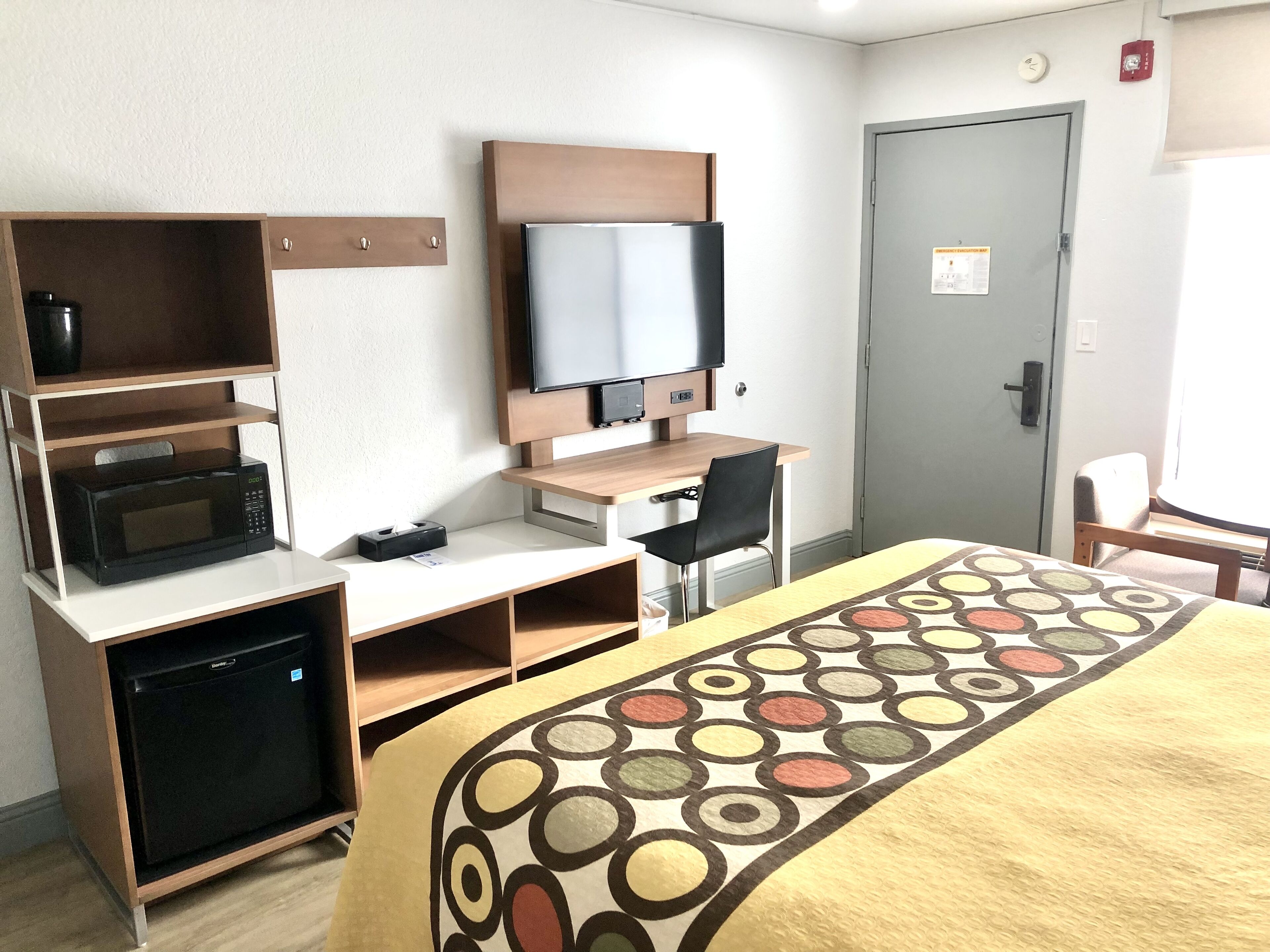 Habitació d'hotel amb llit, escriptori amb ordinador i televisió, microones i nevera petita.