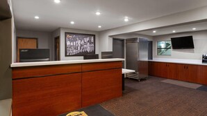 Una cocina moderna con armarios de madera, un refrigerador de acero inoxidable, un televisor de pantalla plana montado en la pared y una puerta con un letrero de 'Super 8'.