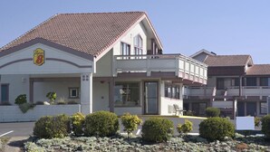 Un hotel con fachada blanca, techo de tejas rojas y un letrero que indica que es un Super 8.