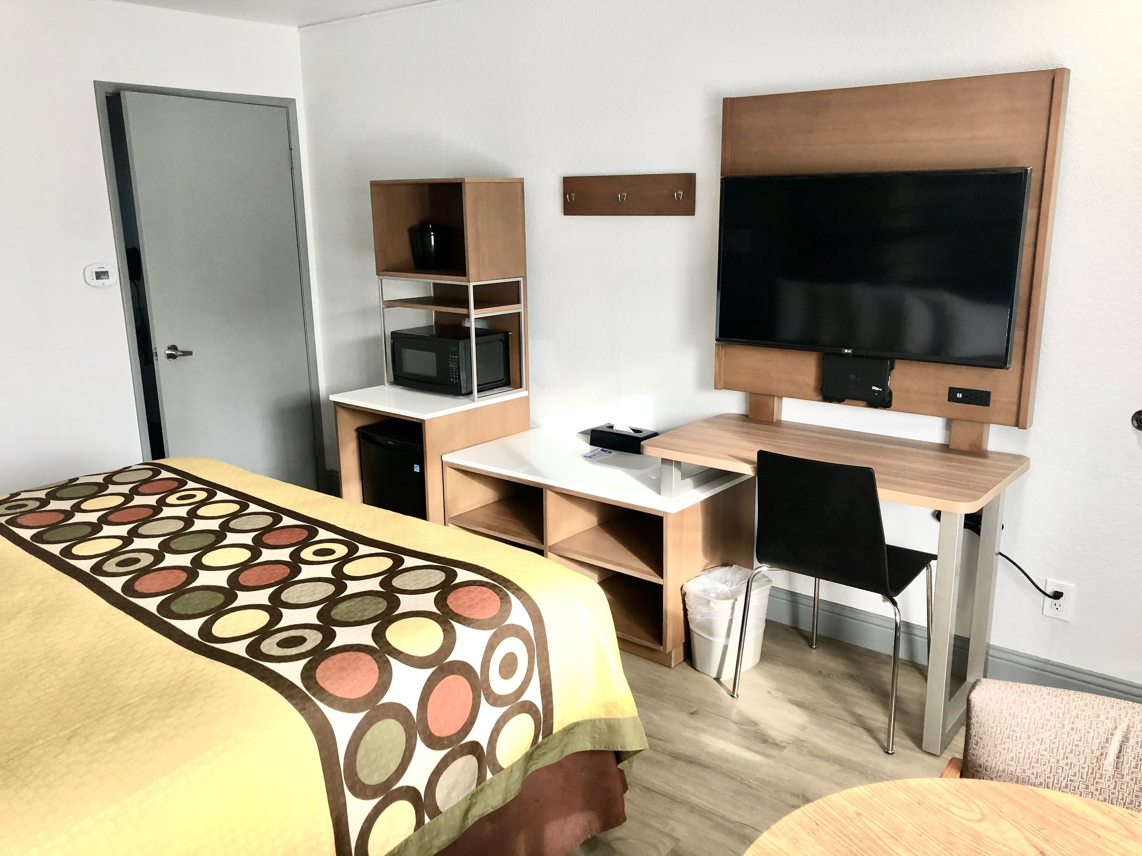 Ein Hotelzimmer mit einem Bett, einem Schreibtisch, einem Sessel, einem Fernseher und einer Mikrowelle.