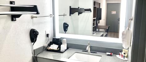 Un baño moderno con un espejo grande, un lavamanos, un perchero para toallas y un secador de pelo.