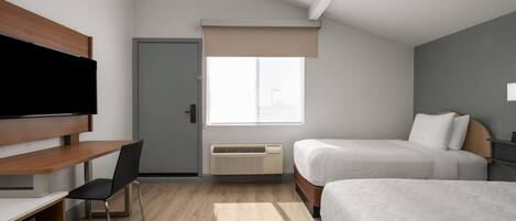 A modern hotel room with a wooden desk, a television, a bed, and a window with a view.