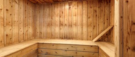 A wooden sauna with a sloped bench and a central light fixture.