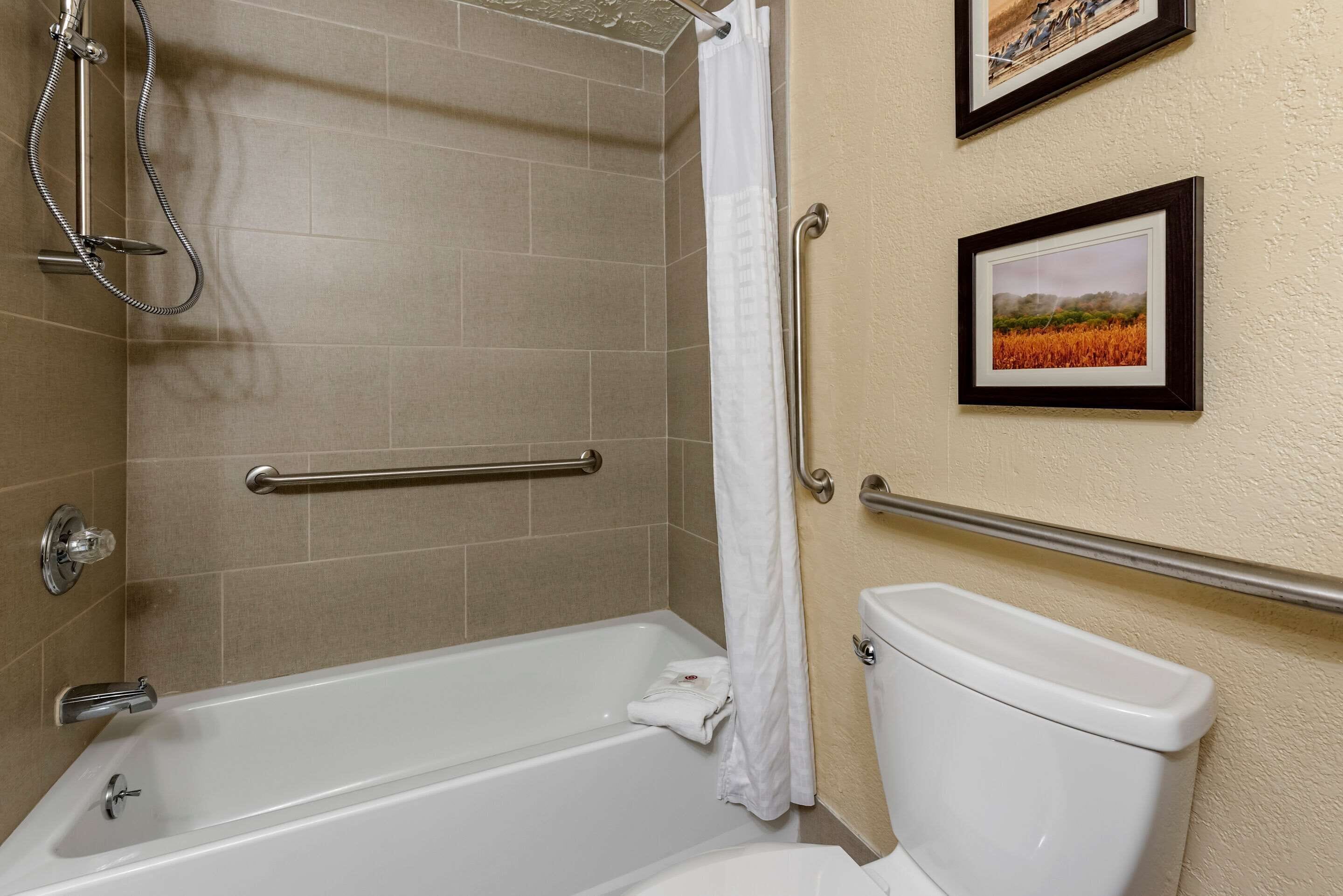 A bathroom with a bathtub, a toilet, and a shower area.